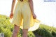 A little girl in a yellow dress standing in a field.