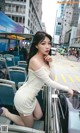 A woman in a white dress sitting on a bus.