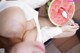 A woman eating a slice of watermelon with a spoon.