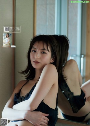 A woman in a black lingerie sitting in front of a mirror.