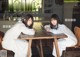 A couple of women sitting at a wooden table.