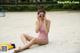 A woman in a pink bathing suit sitting on the beach.