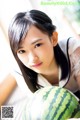 A young woman holding a watermelon in her hands.