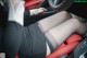 A woman sitting in the driver's seat of a car with her legs crossed.