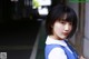 A young woman in a school uniform leaning against a wall.