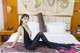 A woman in a black bodysuit sitting on a bed.