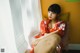 A woman in a red kimono sitting on a window sill.