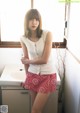 A woman standing in front of a window in a bathroom.