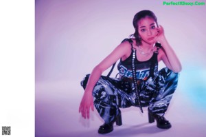 A woman in a black top and silver pants posing for a picture.