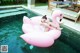 A woman laying on an inflatable pink flamingo floating in a pool.